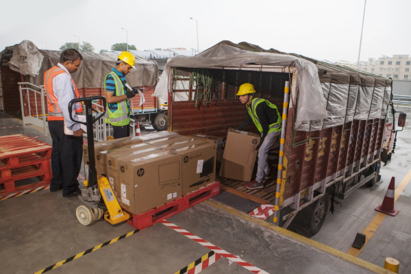 3 Workers hauling packed boxes inside a lorry.